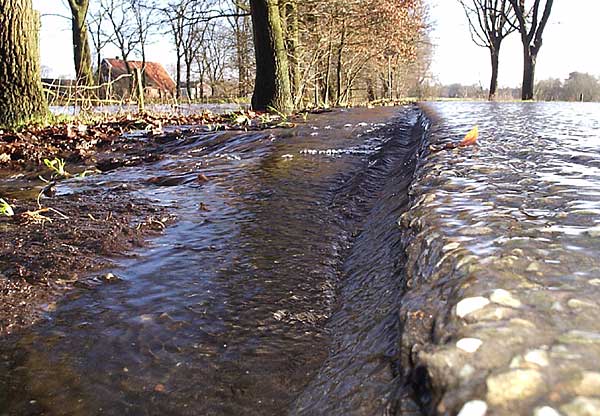 Water stroomt snel over de weg